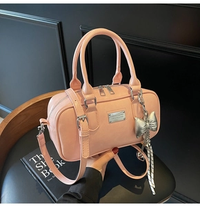 Pink bowling handbag with silver bow charm and adjustable strap shown held by hand
