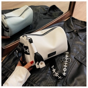 Close-up of white boston bag with litchi texture leather and wide fashion strap