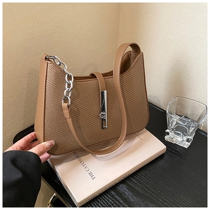 Detail showing brown woven texture and unique silver metal lock on the shoulder bag