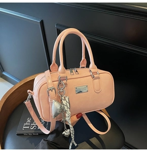 Detailed macro view of pink bowling handbag with silver logo plate and decorative charms