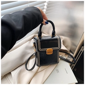 Detail of black leather box bag with gold beads trim and metallic square lock closure
