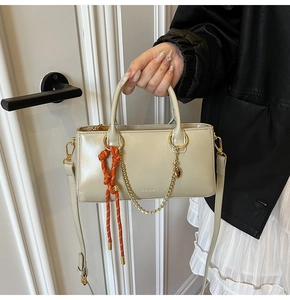 Détail du sac à main blanc crème avec breloque coeur doré et cordon tressé orange vif