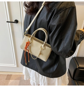 Vue détaillée du sac beige en cuir avec corde tressée orange et détails de chaîne dorée