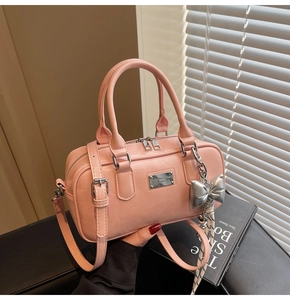 Detail view of pink PU leather Boston bag with silver logo and bow charm accessory