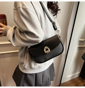 Close-up of black leather crossbody bag with golden U-lock and textured panel detail