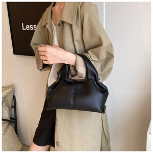 Detail of a black leather cloud bag with lychee texture and vertical stitching