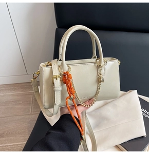 Détail du sac à main en similicuir blanc cassé avec cordon orange et chaîne dorée