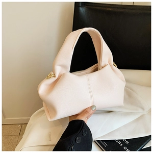 Detail of light pink lychee texture handbag featuring thick top handle and gold metal rings