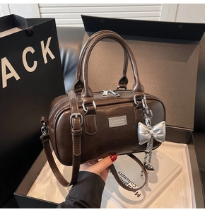 Dark brown leather bowling bag in a black gift box with a silver bow charm detail