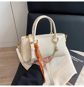 Détail du mini sac cabas crème en cuir avec finitions dorées et breloque orange
