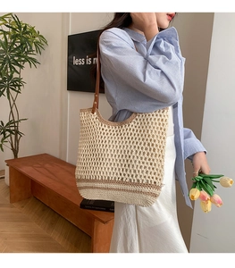 Close-up of beige crochet tote bag with hollow mesh design and brown leather straps