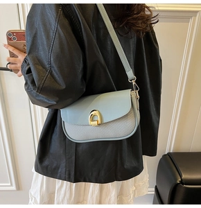Detail showing the light blue leather bag with a woven texture and a gold horseshoe lock