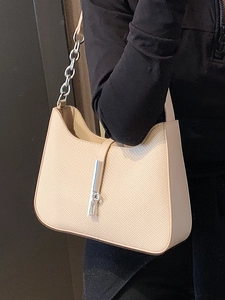 Minimalist beige underarm bag with silver piston lock and chain strap on female model