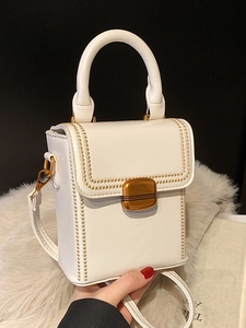 Elegant white glossy leather handbag with gold embroidery and top handle on faux fur