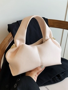 Minimalist light pink cloud bag with lychee texture and golden rings on black blazer