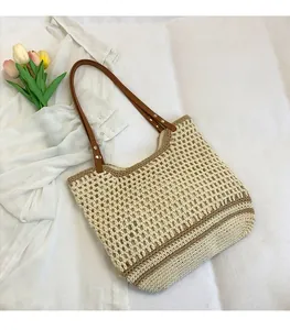 Detail of woven tote bag with beige crochet pattern, brown stripes, and leather straps