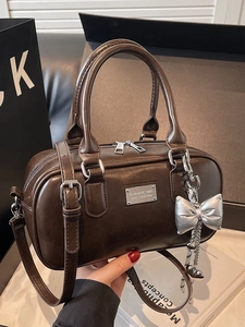 Minimalist brown leather bowling bag for women with silver bow pendant and top handle