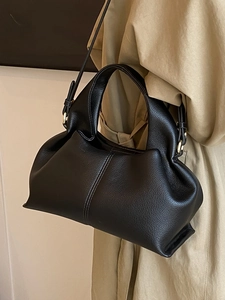 Minimalist black lychee texture dumpling bag with golden hardware and shoulder strap
