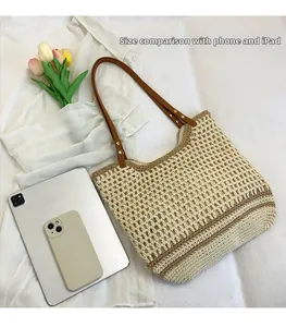 Close-up of woven straw tote bag with brown leather straps and striped knit texture