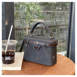 Detailed view of the denim box bag with leather trim and decorative pockets