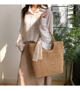 Detail of hand-woven straw tote bag with elegant white lace ribbon on handle