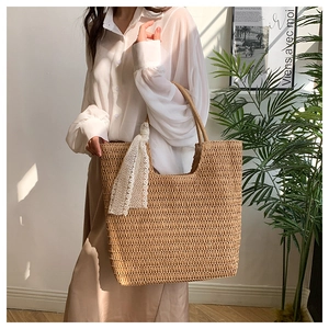 Detail of a large straw tote bag featuring tight woven texture and a white lace scarf