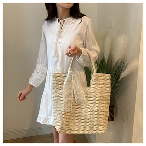 Detail of hand-woven straw tote bag featuring delicate lace bow and intricate texture