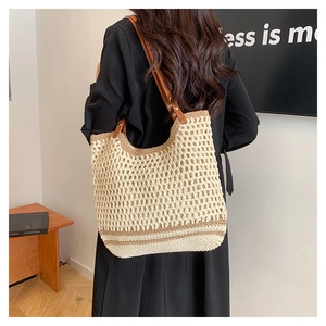 Close-up of woven crochet tote bag featuring brown leather straps and metal rivets
