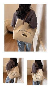 Detail of canvas tote bag showing the leather handles and metal rivet reinforcement