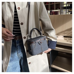Detail view of retro denim shoulder bag with brown leather trim and belt decoration