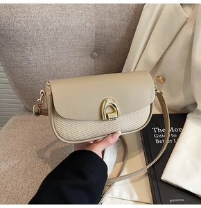 Detail of elegant beige leather and straw woven crossbody bag with gold U-lock on the front