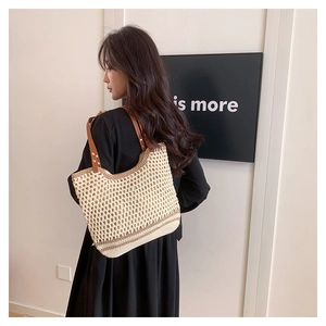 Detail of woven tote bag featuring hollow mesh pattern and brown leather shoulder straps