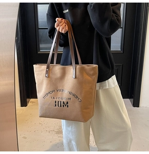 Detail of khaki canvas tote bag with brown leather straps and Cherish Every Moment text