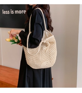 Detail of beige crochet tote bag with openwork mesh design and fringed tassel accents