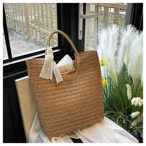 Close-up of handmade woven straw tote bag with elegant white lace bow decoration