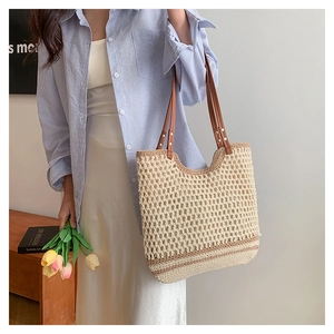Detail of woven beach tote showing beige crochet texture and brown leather handles