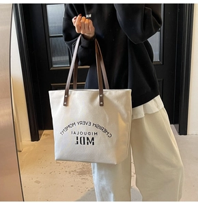 Mirror selfie showing the large canvas tote bag scale with leather straps on a model
