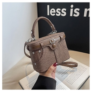 Detail of a brown denim-textured box bag with pocket elements and rivet accents