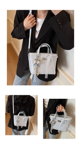 Close-up of light gray oil wax leather tote bag with silver bow pendant and lace detail