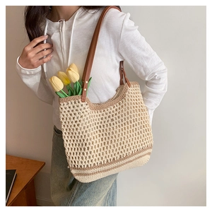 Close-up of woven straw tote bag with brown leather straps and mesh hollow design