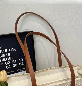 Close-up of woven straw tote bag featuring brown leather shoulder straps and zip closure