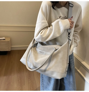 Detail of grey large capacity tote bag with wide strap and minimalist brand logo