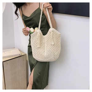 Detail view of the hand-woven hollow knit pattern and long tassels on cream tote bag
