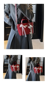 Close-up of red oil wax leather bucket bag with lace bow and silver heart charms