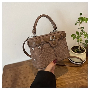 Detail of vintage brown denim texture box bag with metal rivets and leather belt buckle