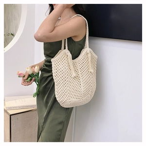 Detail of a cream hand-woven crochet tote bag with fringe tassels and mesh design