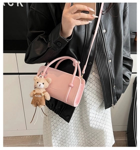 Close-up of pink glossy PU leather handbag featuring a cute plush bear charm accessory