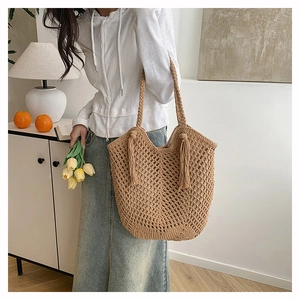 Close-up of woven tote bag featuring large mesh hollow design and stylish long tassels
