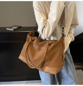 Detail view of large brown canvas tote bag with adjustable shoulder strap and leather patch