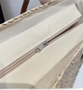 Detailed close-up of smooth silver metal zipper and canvas lining on beige woven tote